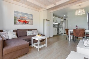Un salon moderne avec un canapé, une petite table et un coin repas avec des chaises.