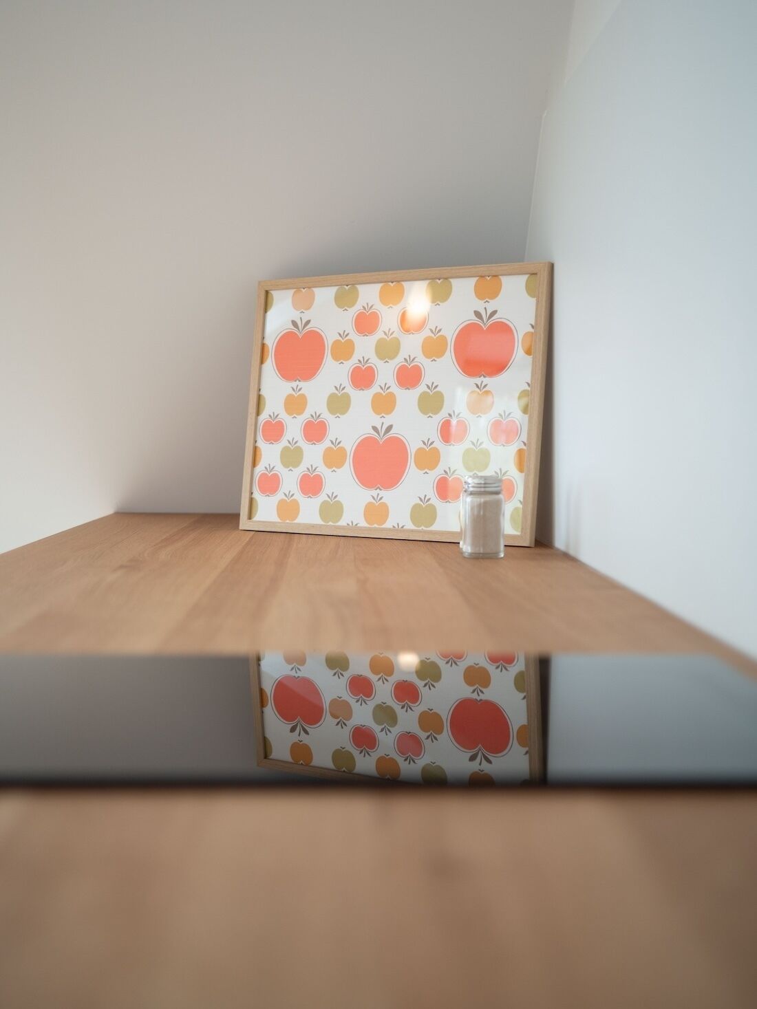 A framed picture with a fruit pattern on a wooden surface.