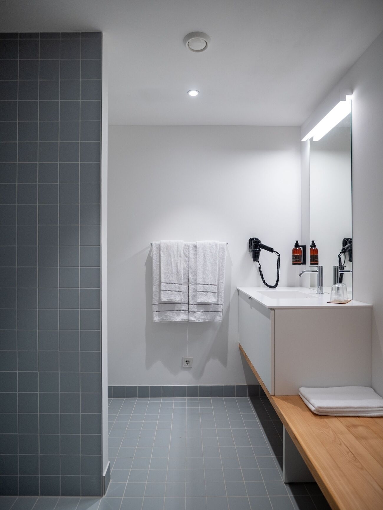 Casa de banho moderna com lavatório branco, espelho e porta-toalhas.