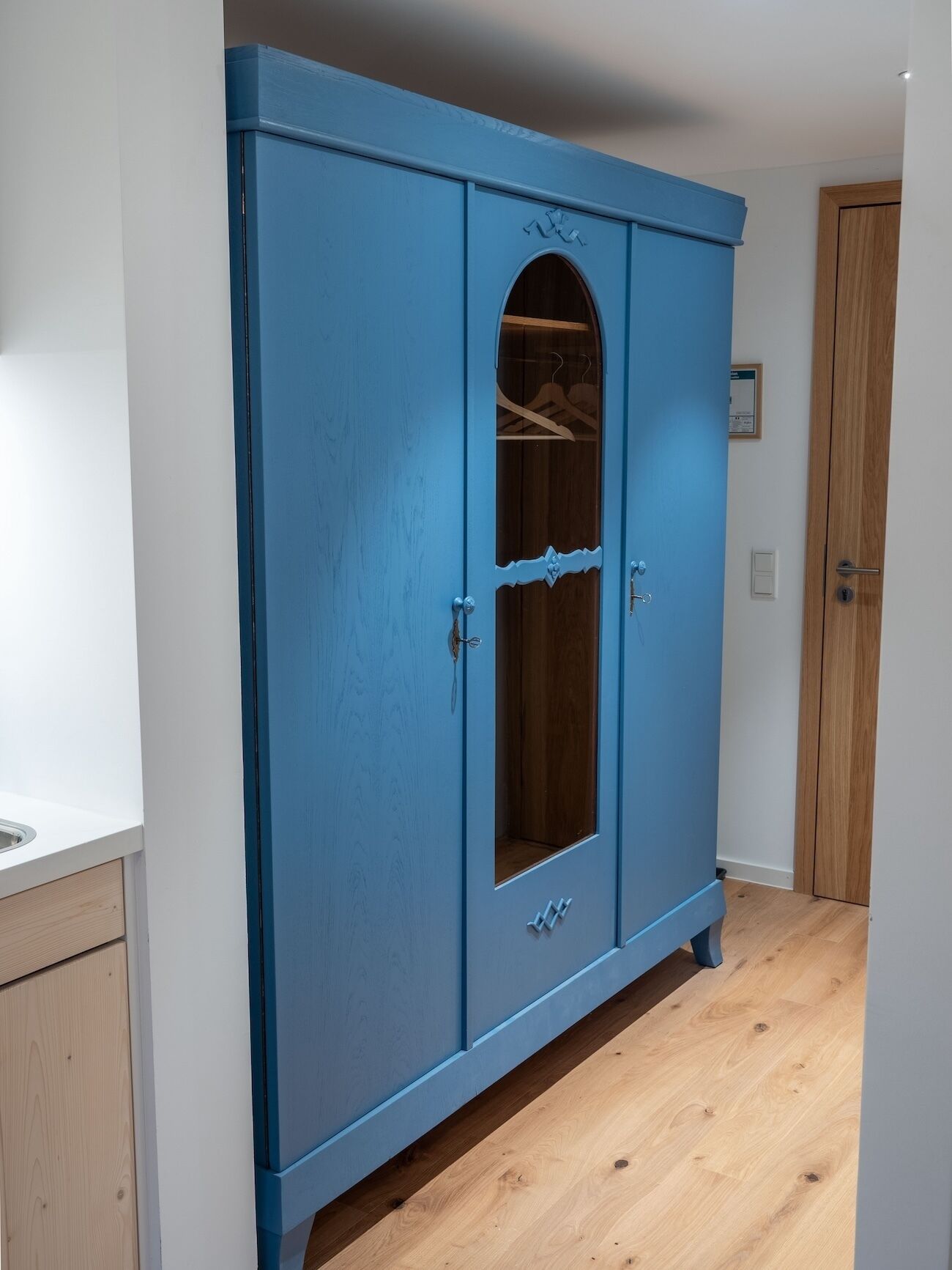 Un armario azul con una puerta de espejo y una puerta de madera.