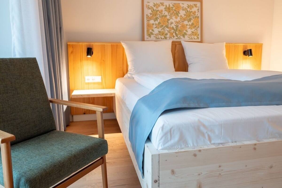 Une chambre à coucher avec un lit, une chaise et une table de chevet avec une lampe.