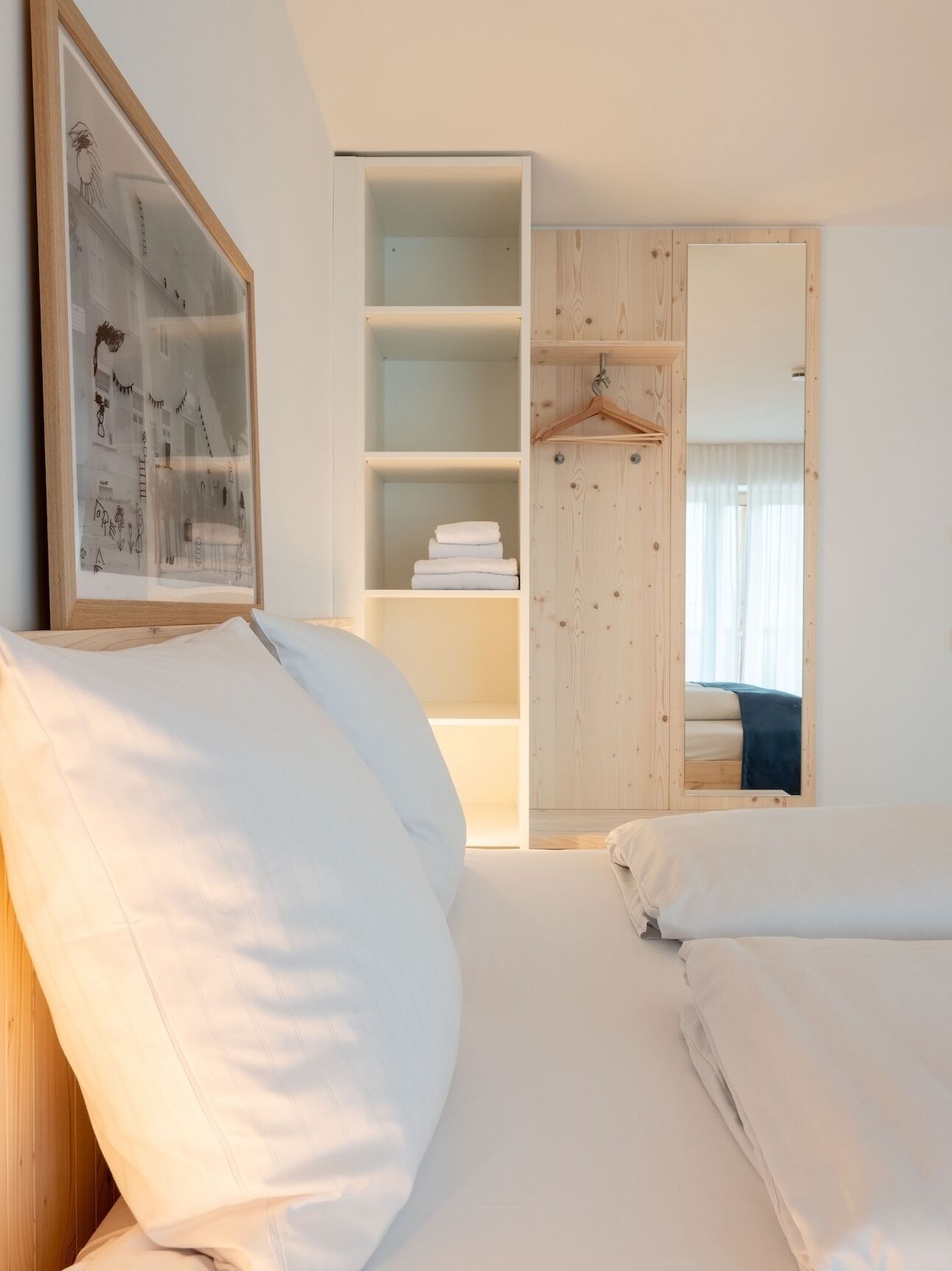 A bedroom with a large bed, a wardrobe with multiple shelves, and a framed picture on the wall.