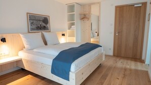 Un dormitorio con cama de madera, una mesita de noche, un armario y un cuadro enmarcado en la pared.
