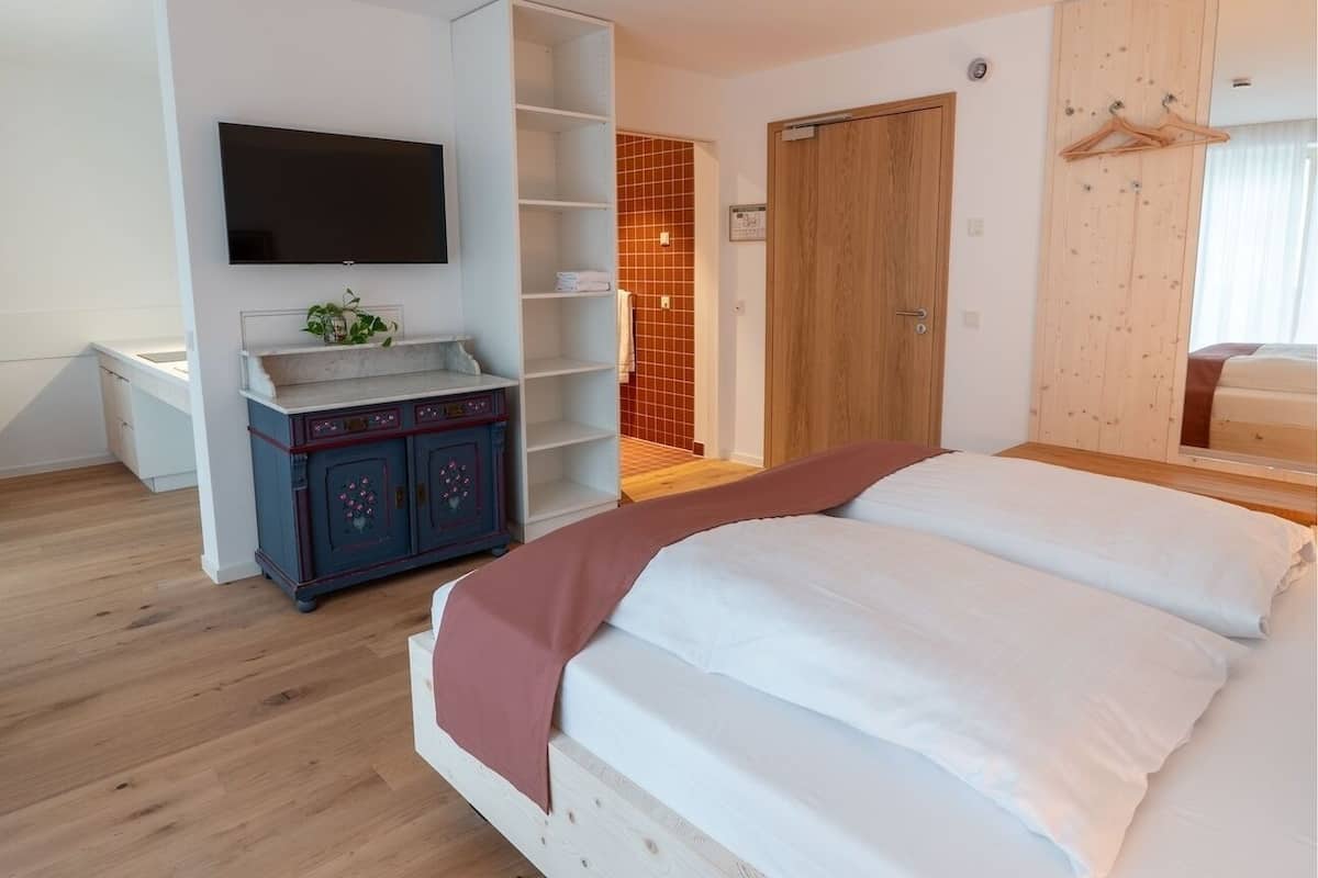 Une chambre à coucher comprenant un lit, une télévision, une armoire et un petit meuble.