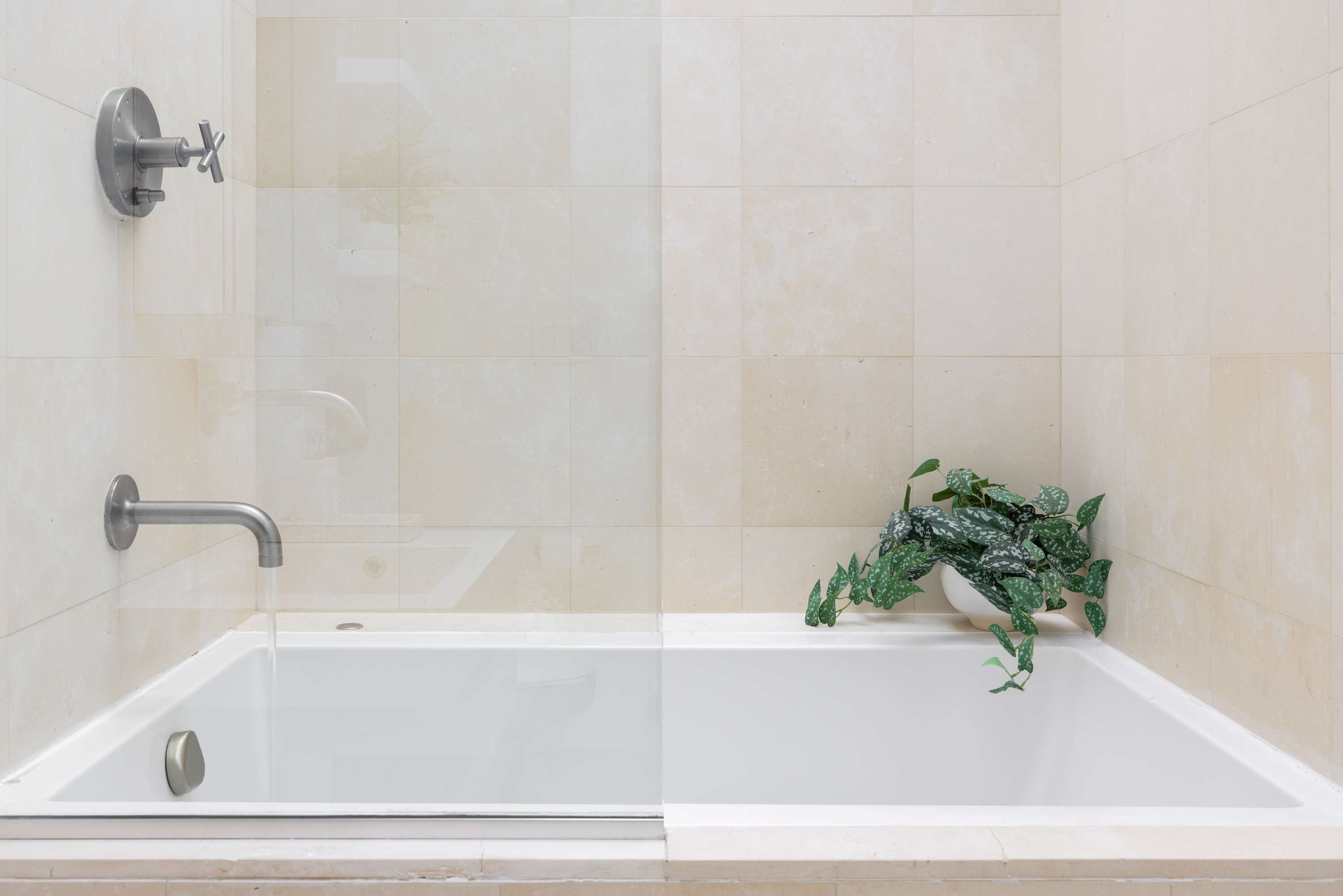 Ein modernes Badezimmer mit Badewanne, Duschkopf und einem Blumentopf.