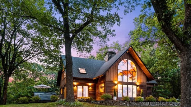 A large, rustic log cabin with a prominent gabled roof, surrounded by lush greenery and trees. - Catskill Estate w Epic Views hot tub (Kingston)
