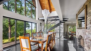 A spacious dining area with a high ceiling, large windows, and a view of the outdoors. - Catskill Estate w Epic Views hot tub (Kingston)