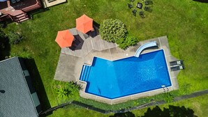 An aerial view of a backyard with a swimming pool, two orange umbrellas, and a small garden area. - HV Spacious Retreat Sleeps 13 w Hot Tub (Poughkeepsie)