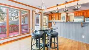 A modern kitchen with wooden cabinets, a glass dining table, and bar stools. - HV Spacious Retreat Sleeps 13 w Hot Tub (Poughkeepsie)