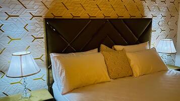 A neatly made bed with a geometric patterned headboard, a bedside lamp, and a wall with a similar geometric pattern.