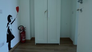 A hallway with a white wardrobe, a fire extinguisher, and a wall decal of a girl holding a heart. - Grimani Suite (Milan)