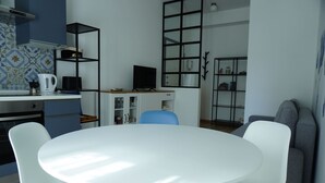 A modern kitchen with a white table and blue chairs, a built-in oven, and a coffee maker. - Grimani Suite (Milan)