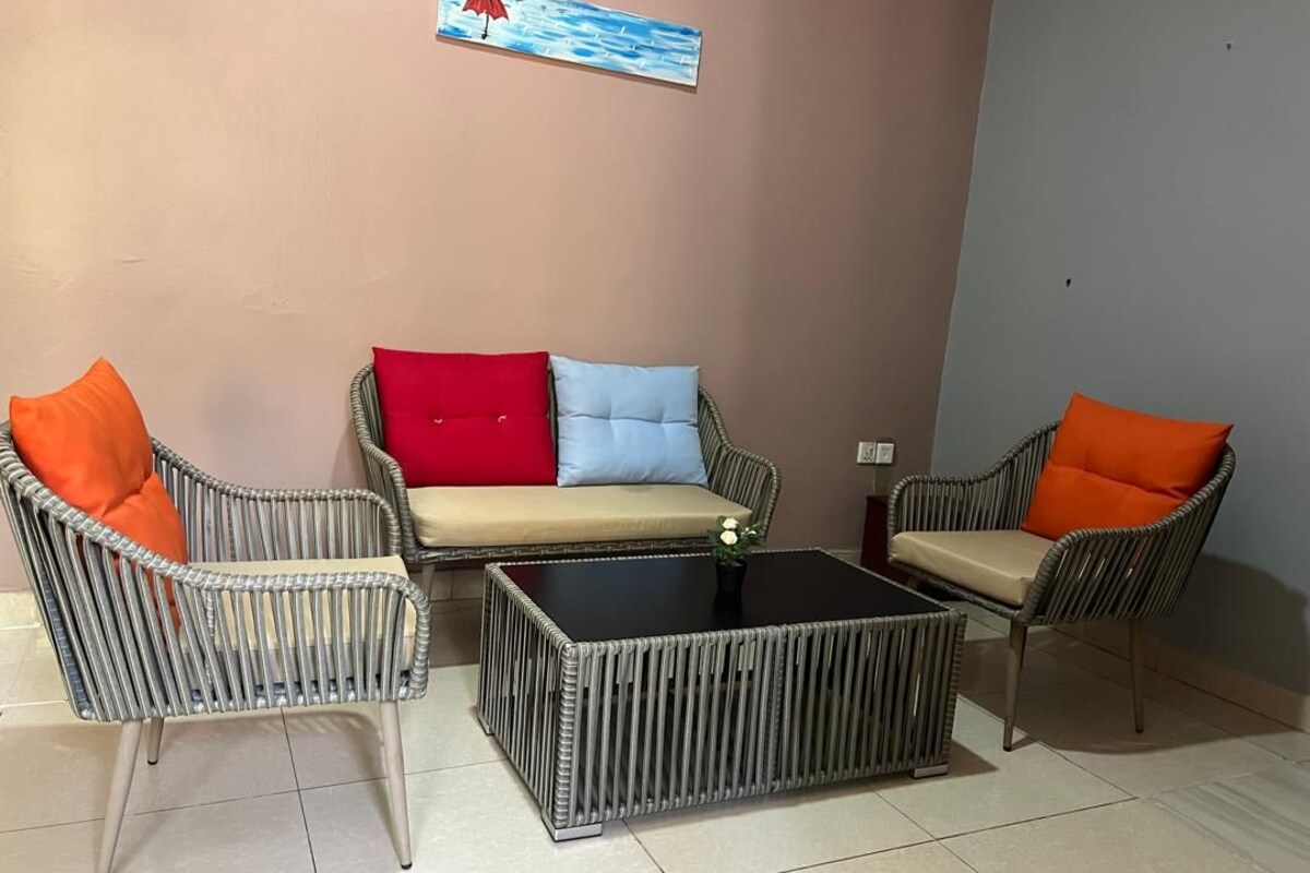 A seating area with wicker chairs and a sofa, a coffee table, and a wall-mounted painting.