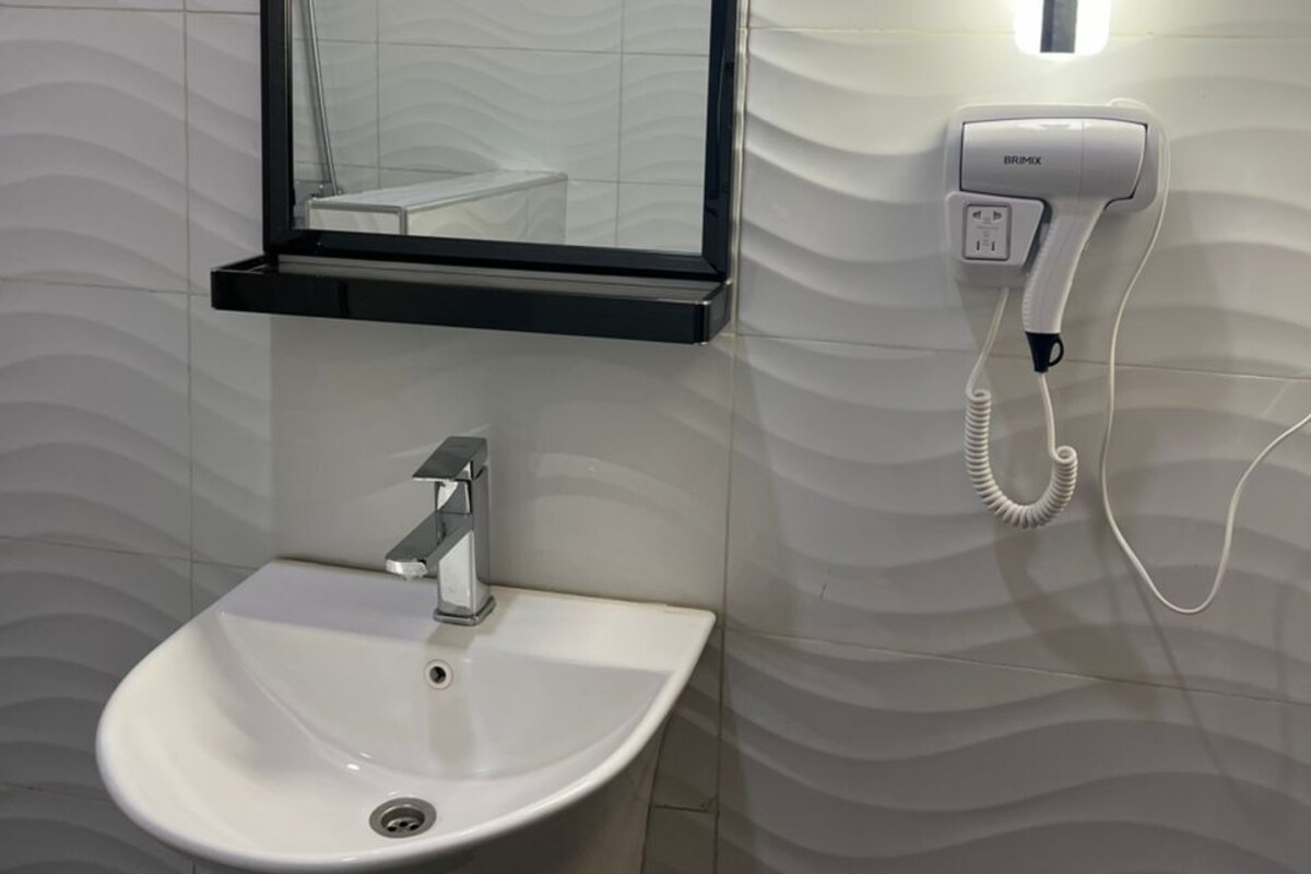 A bathroom with a white sink, a mirror, and a wall-mounted phone.