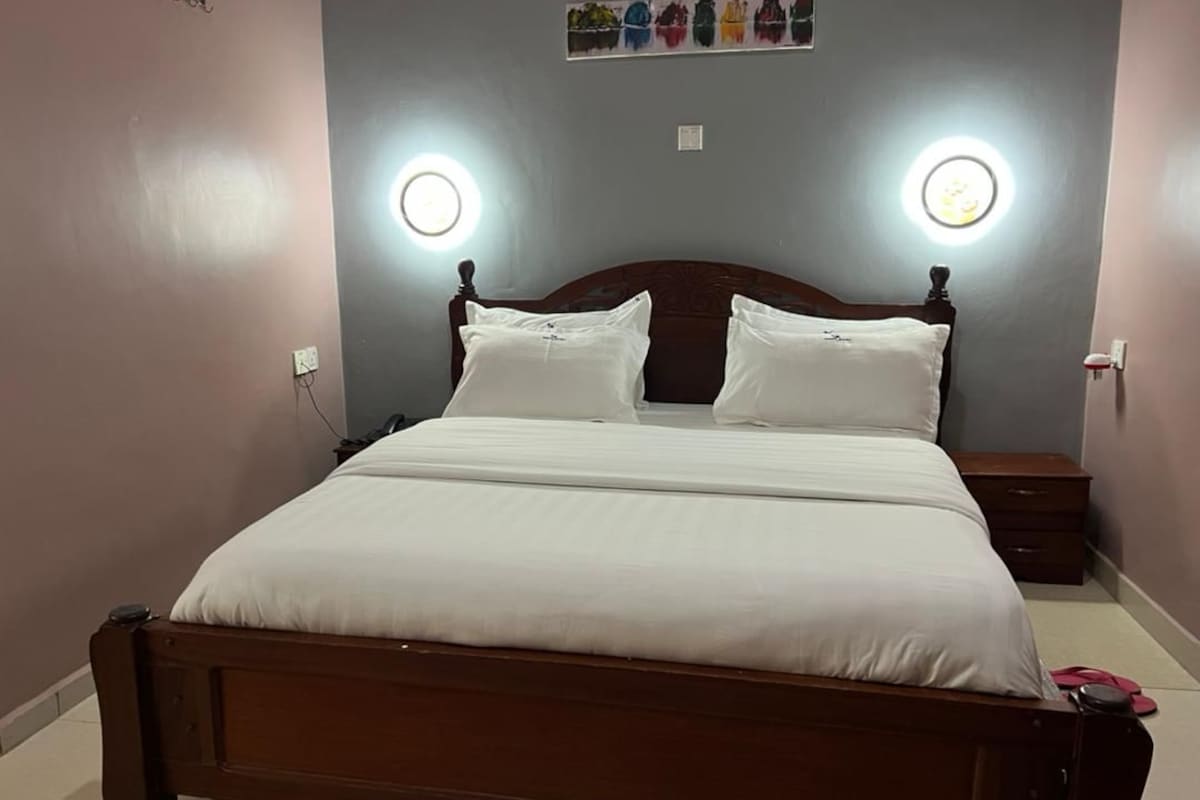 A neatly made bed with white linens, two bedside tables, and wall-mounted lights.