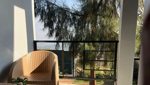 Ein Balkon mit einem Korbstuhl und einem kleinen Tisch mit einem Blumentopf.