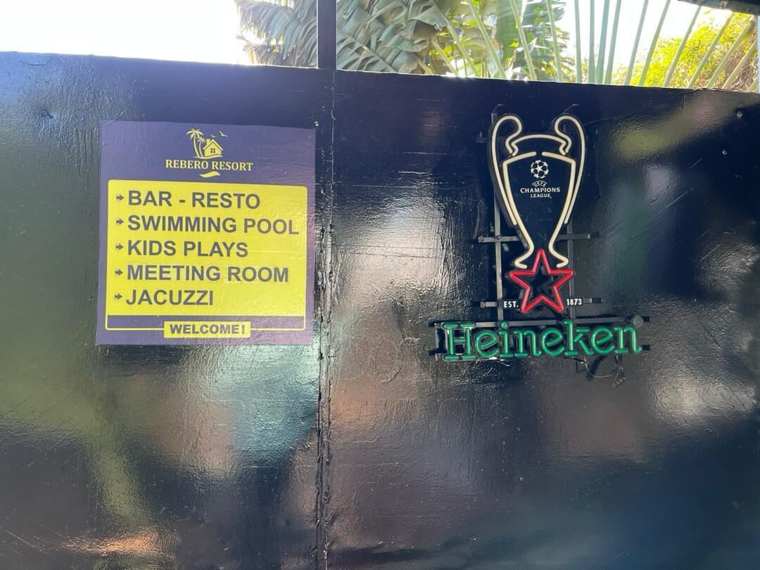 A sign listing amenities such as a bar, restrooms, swimming pool, kids' plays, meeting room, and jacuzzi at Rebero Resort.