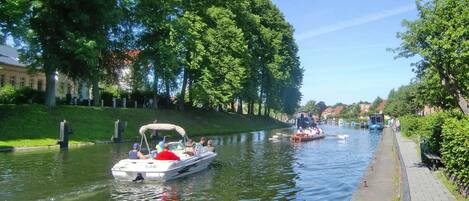 A canal with boats, trees, and a paved walkway.