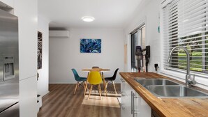 Eine kleine Küche mit einer Holz Arbeitsplatte, einem Edelstahl-Spülbecken und einem Essbereich mit rundem Tisch und Stühlen.