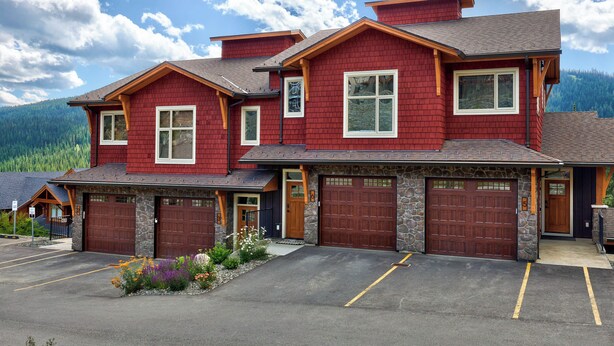 A two-story building with a red exterior, stone accents, and a garage with two doors.