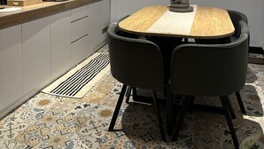 Una cocina moderna con una mesa de comedor de madera, sillas negras y un ventilador de techo.