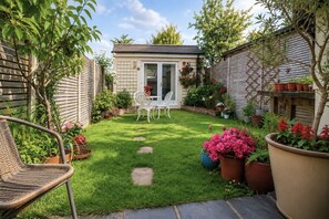 A well-maintained garden with a patio area, a white chair, and a small table. - Garden room, central Winchester – self-contained, kitchenette & parking (Winchester)