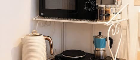 A kitchen counter with a microwave, a coffee maker, and a kettle.