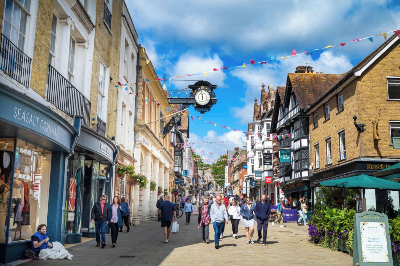 Une rue piétonne bordée de boutiques et surmontée d’une tour de l’horloge.