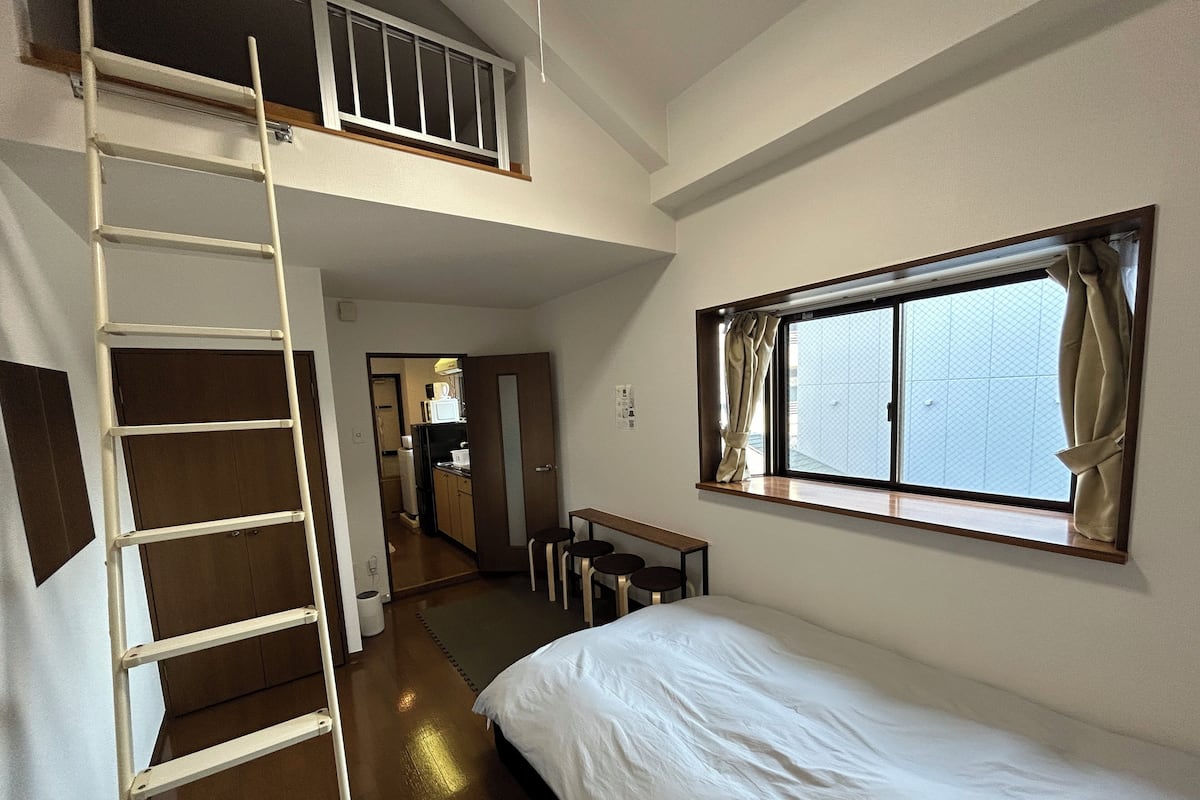 A bedroom with a bunk bed, a desk, a chair, and a window with curtains.