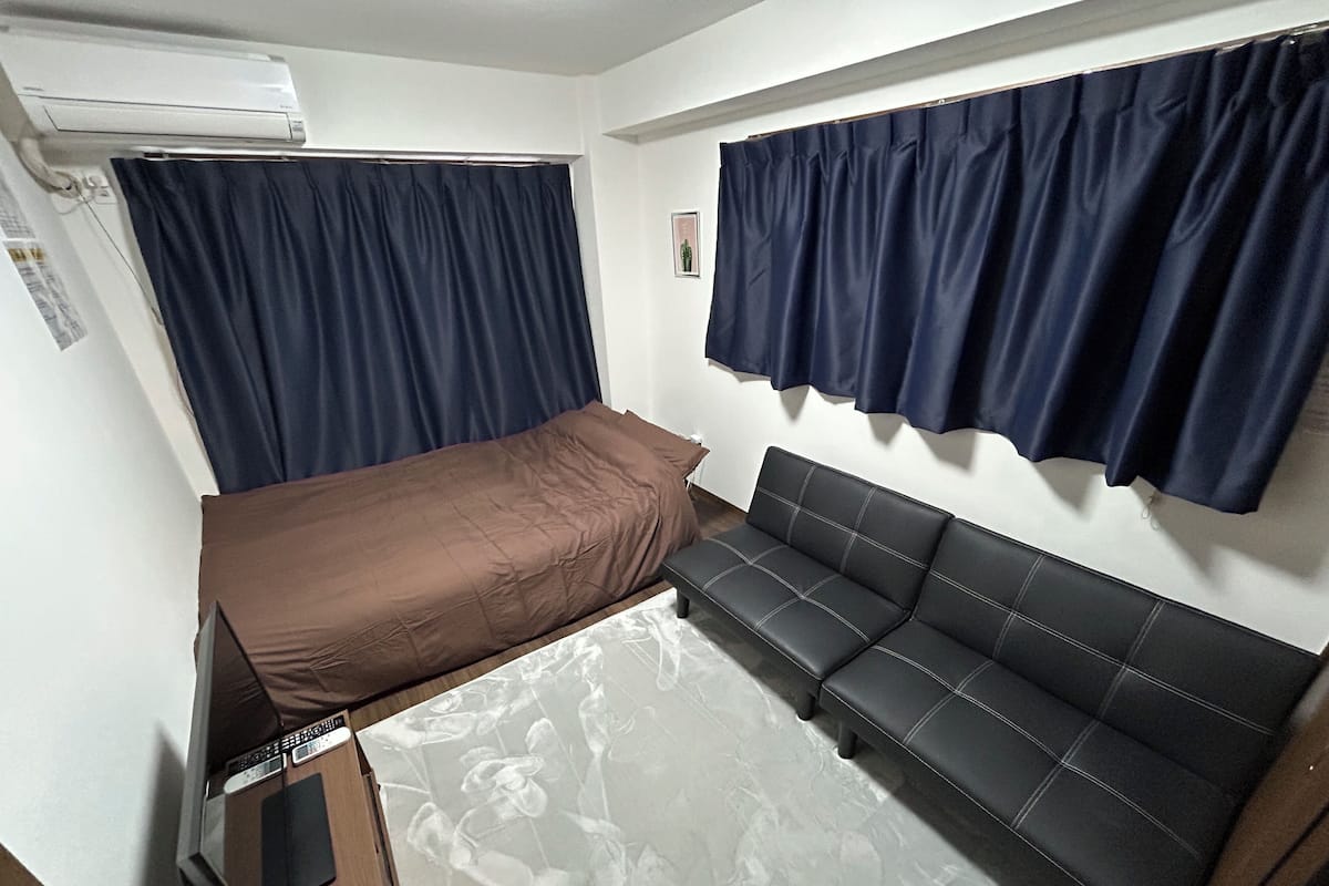 A compact room with a bed, a sofa, and a small table.