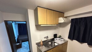 A compact kitchen with wooden cabinets, a stainless steel sink, and a small countertop.