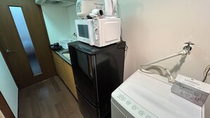 A compact kitchen with a microwave, a small refrigerator, and a washing machine.