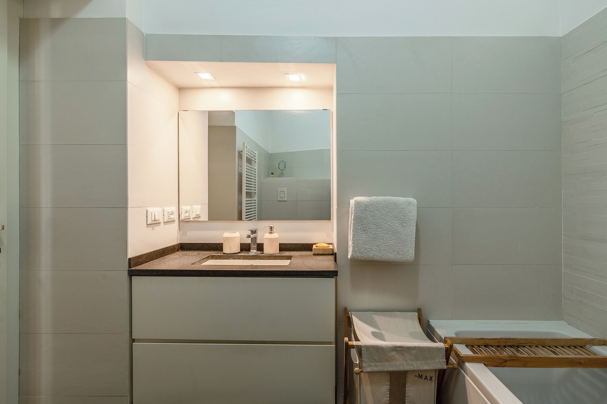 A modern bathroom with a sink, mirror, towel rack, and a shower area.