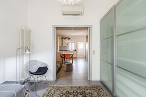 A modern interior with a glass partition, a dining area, and a kitchen visible through an open doorway.