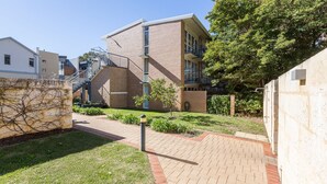 A residential building with a brick facade, a small garden area, and a paved walkway. - Cottesloe Tree Top Studio (Cottesloe)
