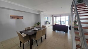 A dining area with a table and chairs, a sofa, and a staircase.