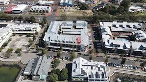 An aerial view of a waterfront property with modern buildings, a marina, and a parking area.