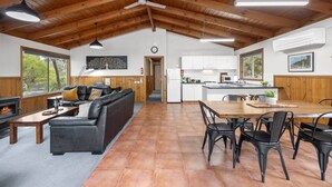 Een ruime woonkamer met een open haard, een bank en een eettafel met stoelen.
