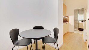 Un espace repas moderne avec une table ronde et quatre chaises, une cuisine dotée d’un plan de travail en marbre et d’un plancher en bois.
