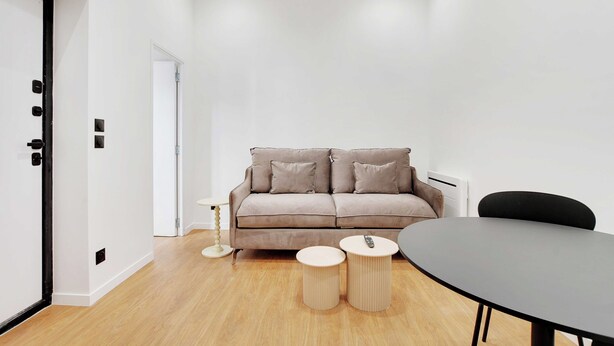 Un salon moderne avec un canapé, deux petites tables d’appoint et une table de salle à manger ronde.