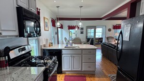 Une cuisine équipée d’une cuisinière à gaz, d’un four à micro-ondes, d’un réfrigérateur et dotée d’un plancher en bois.