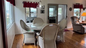 Un coin repas avec des chaises en osier, une table en verre et un ventilateur de plafond.