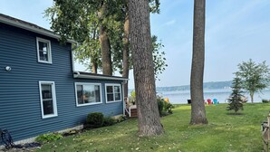 Une maison à l’extérieur bleu, avec une cour verdoyante et une vue sur un lac.