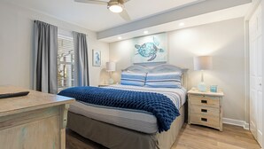 A bedroom with a bed, bedside tables, a ceiling fan, and a wall-mounted artwork.