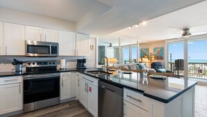 A modern kitchen with stainless steel appliances, white cabinetry, and a large island with a sink.