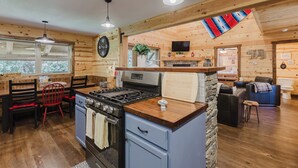 A cozy cabin-style kitchen with a stove, sink, and dining area.