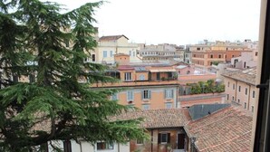 Une vue d’un quartier résidentiel avec plusieurs immeubles, dont une maison avec un toit en tuiles et un arbre au premier plan.
