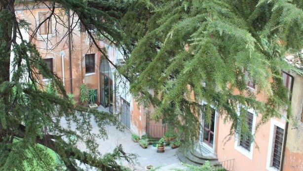 Une cour intérieure avec un bâtiment dont la façade est rouge et qui possède de nombreuses fenêtres.