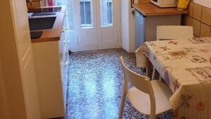 Une cuisine compacte comprenant un coin repas, un four à micro-ondes et une petite table recouverte d’une nappe à motifs floraux.