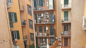 Un immeuble résidentiel à plusieurs étages, doté de balcons, d’une terrasse sur le toit avec mobilier d’extérieur et d’une piscine.
